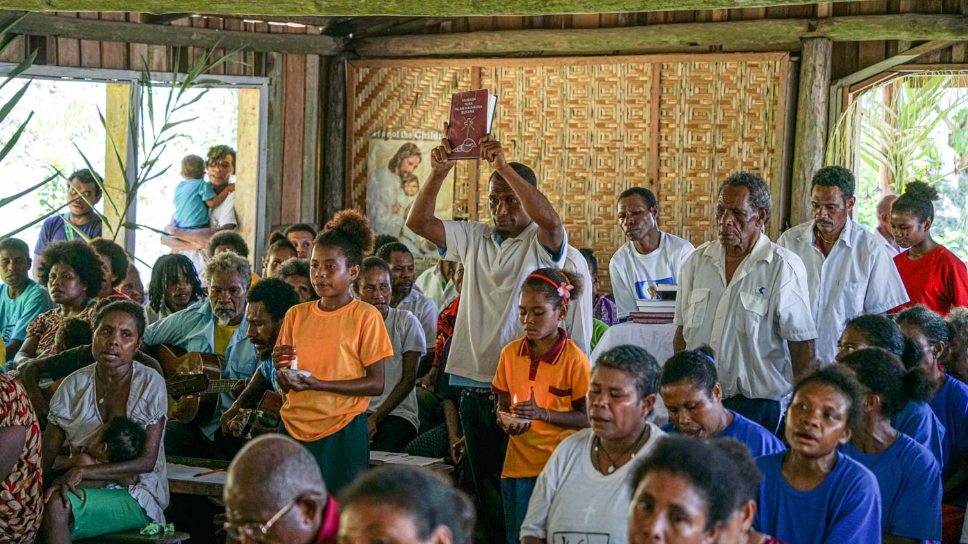 Member of the Saliba church holds up a New Testament.